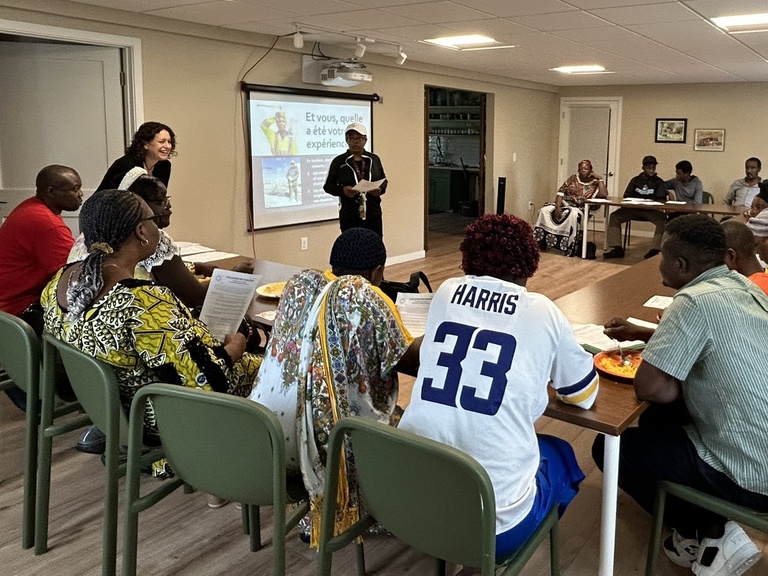 A group of people listening to educators give a presentation at the Immigrant Welcome Network